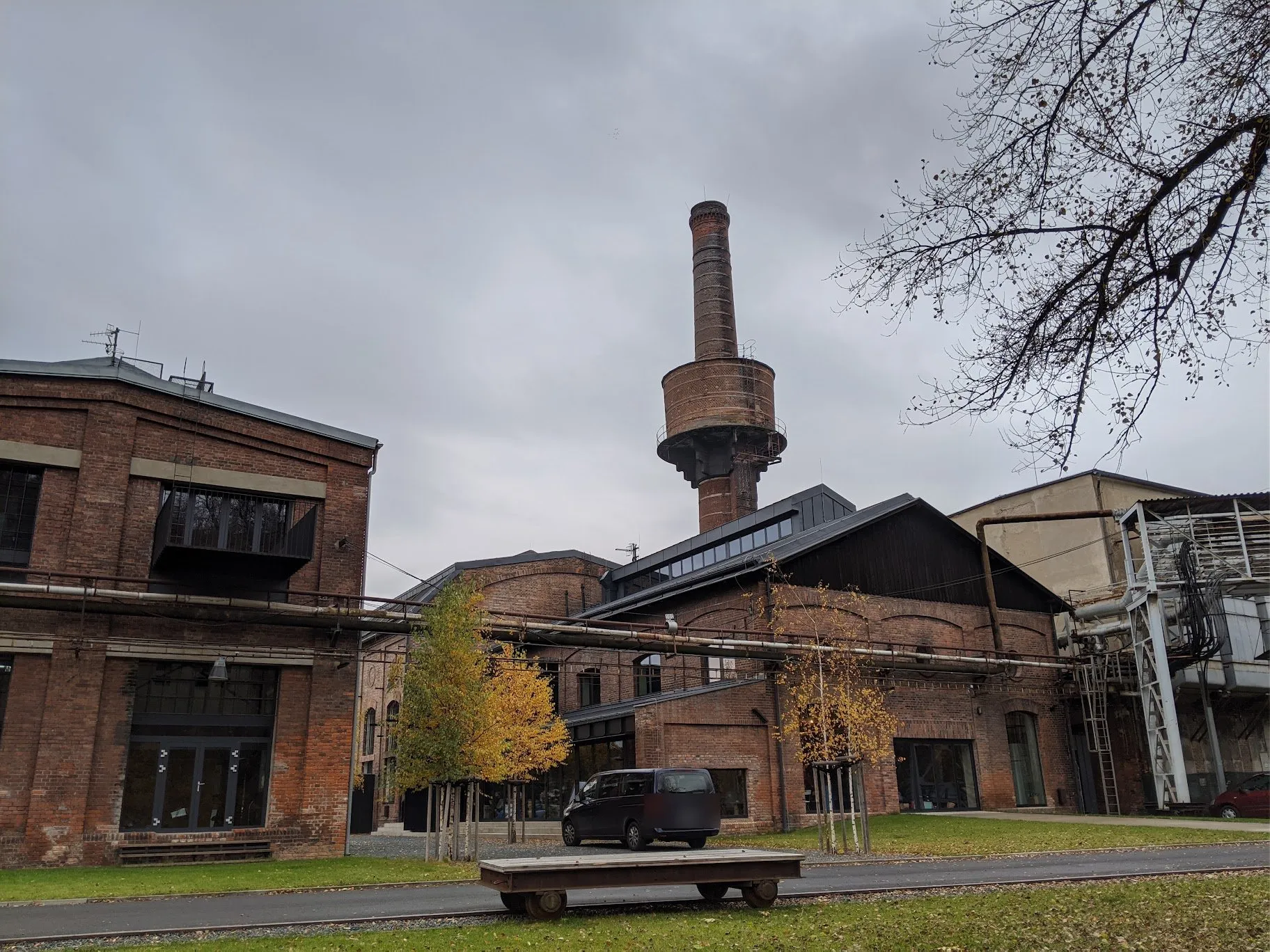 The Uhelný Mlýn complex: red-brick factory halls with a tall brick chimney behind them.