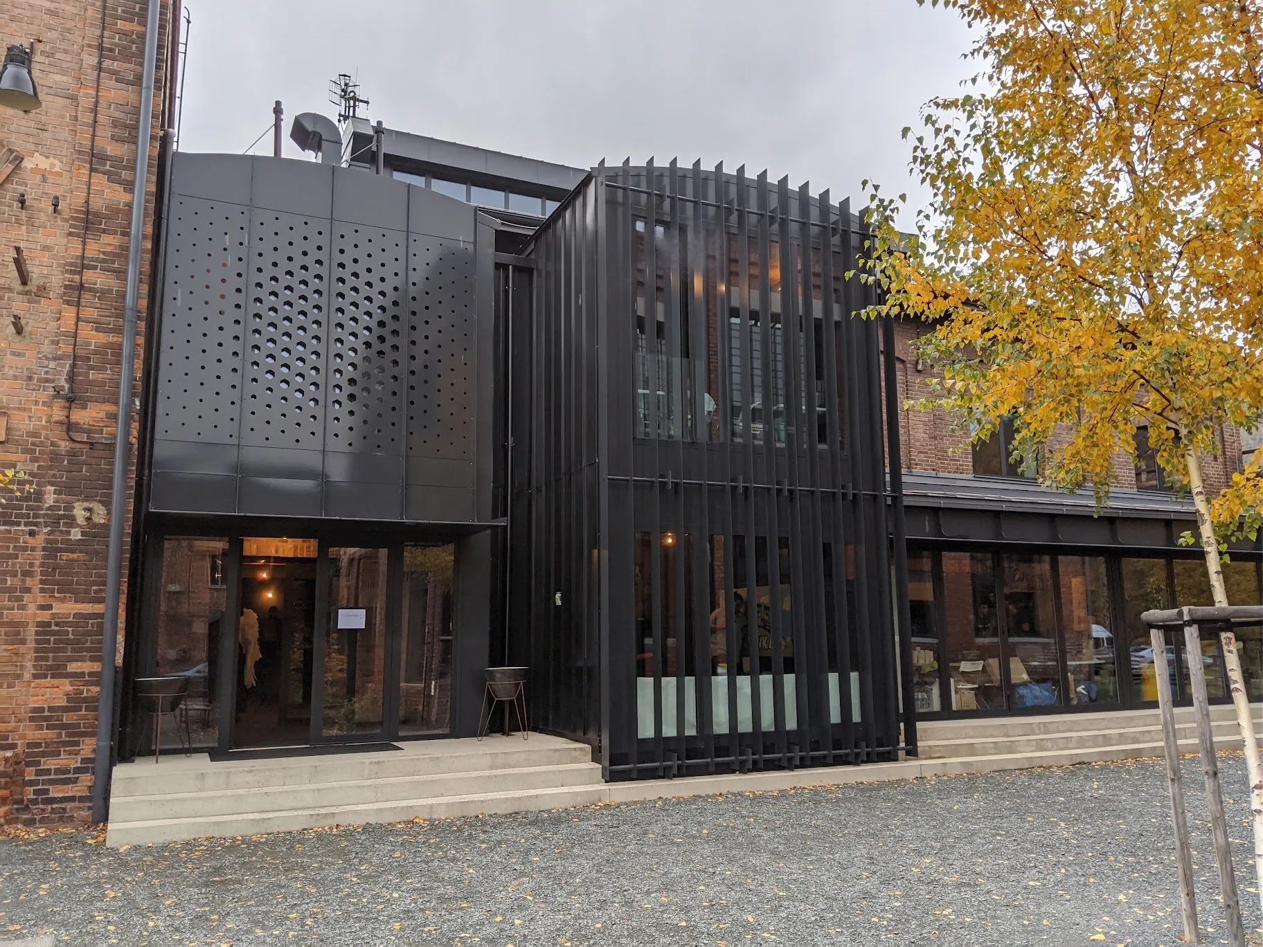 The entrance: glass doors under a black perforated-metal façade, up a few concrete steps.